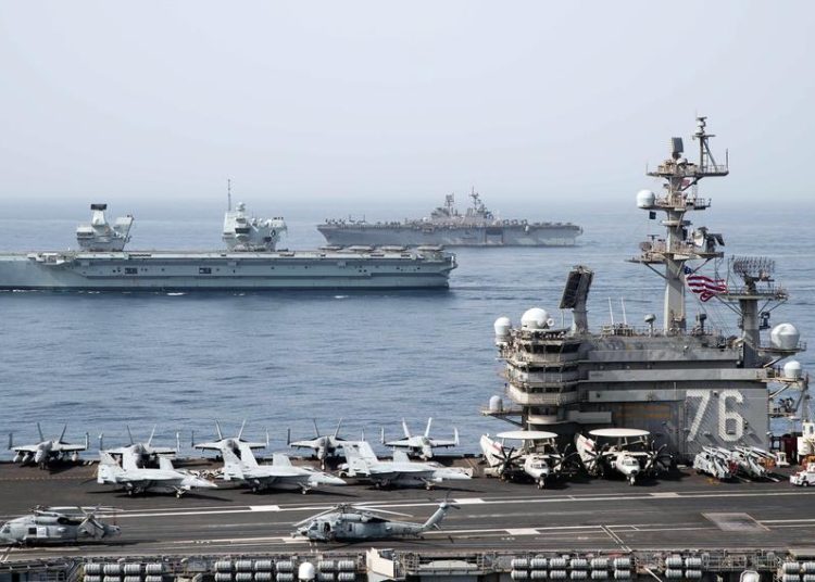 O porta-aviões USS Ronald Reagan, em primeiro plano, o porta-aviões da Royal Navy HMS Queen Elizabeth, no centro, e o navio de assalto anfíbio USS Iwo Jima atravessam o Golfo de Aden, segunda-feira, 12 de julho de 2021. (Jason Tarleton / Marinha dos EUA)